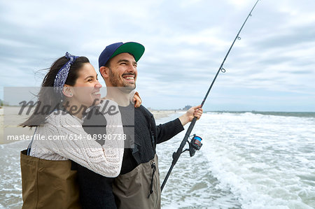 Young couple in waders sea fishing