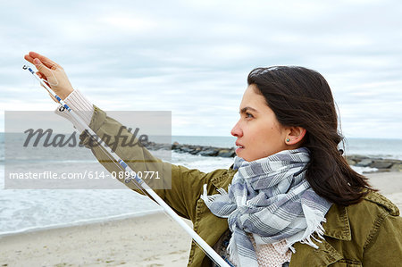 Young woman adjusting fishing rod line on beach