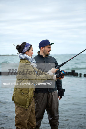 Young man teaching girlfriend sea fishing in sea