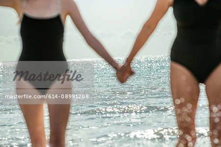 Mother and daughter holding hands on beach, Folkestone, UK