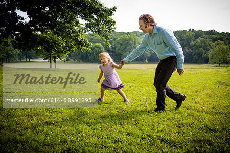Girl running in rural field with father