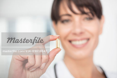 Woman holding pill smiling