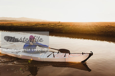 Mid adult woman kayaking on river at sunset, Morro Bay, California, USA