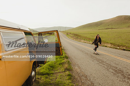 Young male skateboarder skateboarding on rural road, Exeter, California, USA