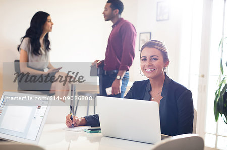 Portrait of young businesswoman using laptop at desk