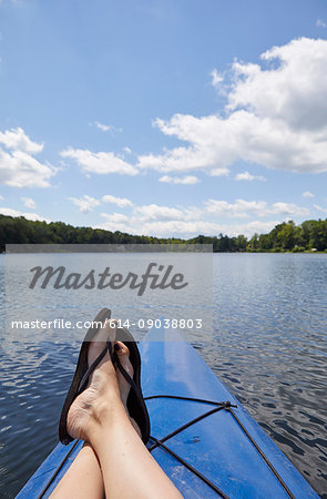 Woman relaxing on canoe, on lake, low section