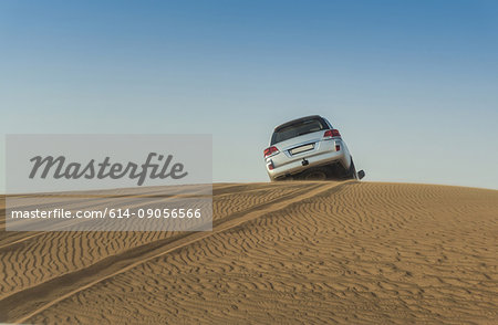 Off road vehicle driving over top of desert dunes, Dubai, United Arab Emirates