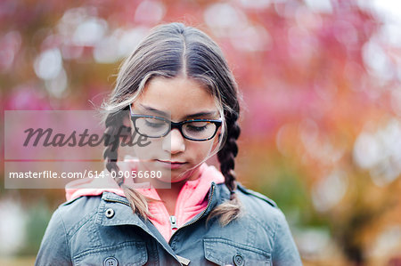 Portrait of girl with plaits and glasses looking down