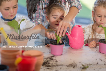 Mid adult woman helping young children with gardening activity