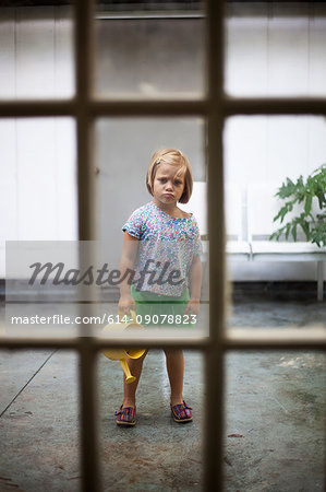 Girl with watering can standing stubbornly still