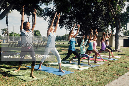 Schoolgirls practicing yoga warrior one pose on school sports field