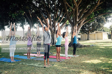 Schoolgirls practicing yoga pose on school sports field