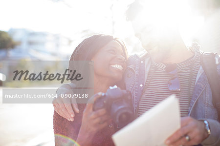 Man and woman outdoors, woman holding camera, smiling