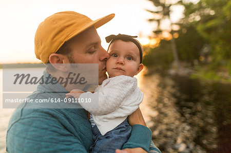 Man kissing baby daughter at lakeside