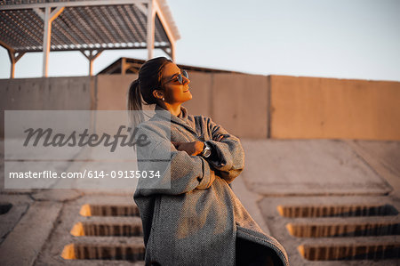 Portrait of woman wearing sunglasses and winter coat, arms folded, looking away smiling, Odessa, Odeska Oblast, Ukraine, Eastern Europe