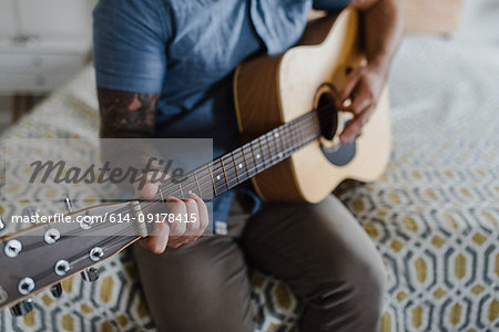 Guitarist playing music on bed