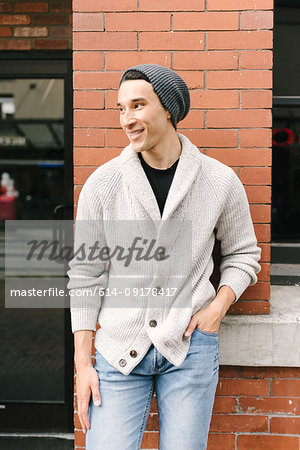 Young man leaning against brick wall, Vancouver, Canada