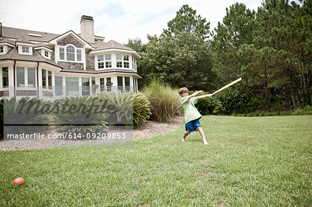 Boy swinging baseball bat in field