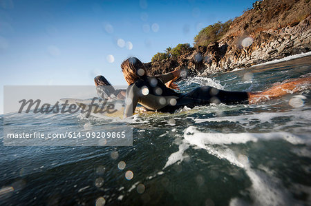Surfers paddling in ocean
