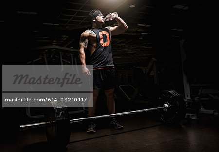 Man drinking water from a bottle at a gym - Stock Photo - Masterfile