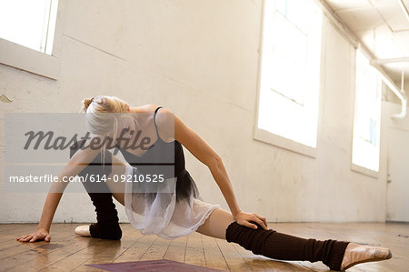 Ballet dancer stretching leg in studio