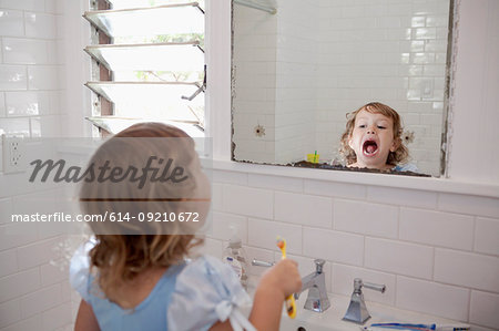 Female toddler looking in mirror cleaning teeth
