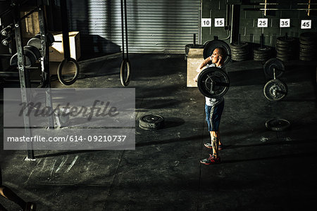 Young man training with barbell in gymnasium