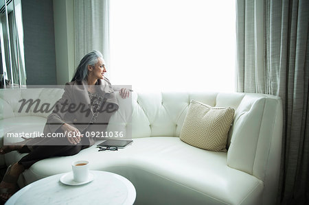 Portrait of mature woman reclining on white luxury sofa