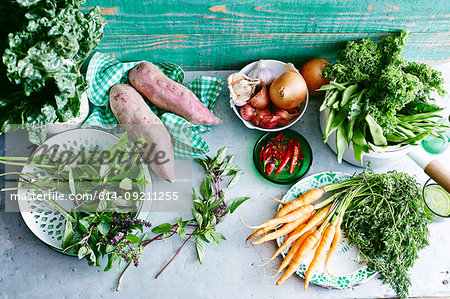 Still life of fresh mint, sweet potatoes, baby carrots, chillies, onions, garlic, eschallots, green beans, kale and silverbeet