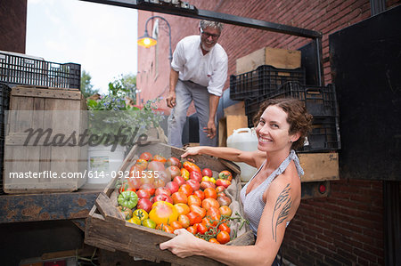 Farmers unloading crates of organic tomatoes outside grocery store