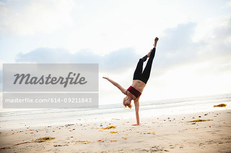 Mid adult woman practicing yoga position on beach