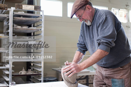 Side view of potter in workshop kneading clay