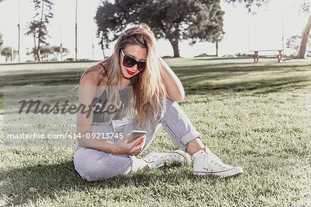 Hip young woman using mobile phone in park