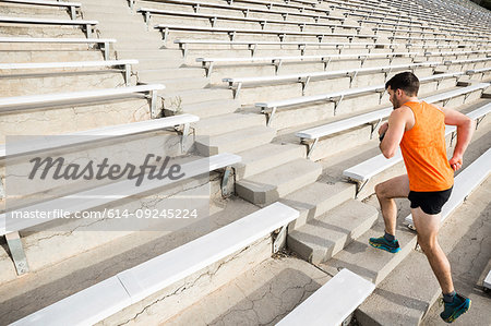 Young male runner running up stadium stairway