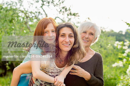 Girl getting piggyback with mother and grandmother in garden, portrait