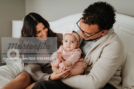 Couple with baby daughter on bed in bedroom