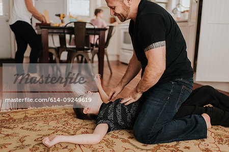 Father and son wrestling on carpet at home