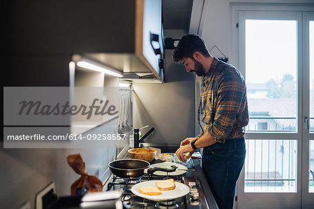 Mid adult man preparing food at kitchen hob