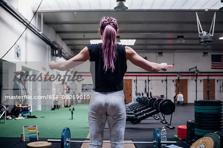 Young woman preparing to lift barbell in gym