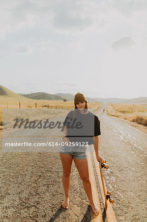Young female skateboarder on rural road, portrait, Exeter, California, USA
