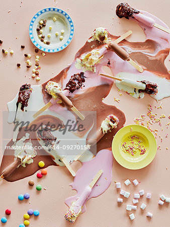 Chocolate top ice lollies melting and sprinkles on table