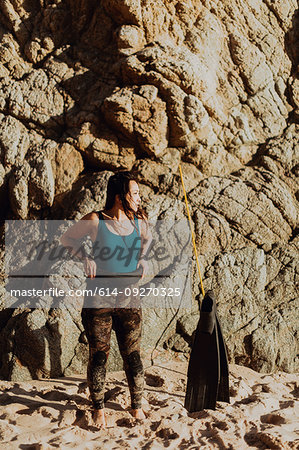 Woman with flippers on beach, rock face in background, Big Sur, California, United States