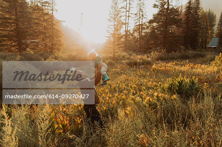 Mid adult man holding up toddler daughter in rural valley at sunset, Mineral King, California, USA