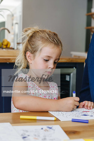 Little girl colouring picture at home