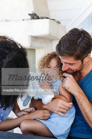 Couple hugging and tickling daughter in beach house