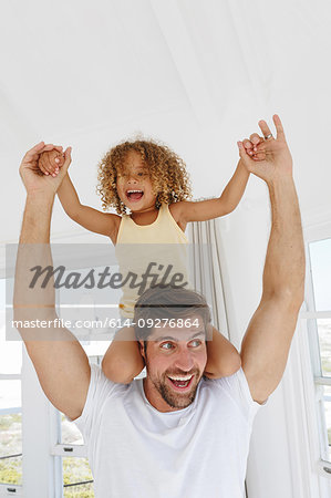 Father giving daughter piggyback ride in beach house