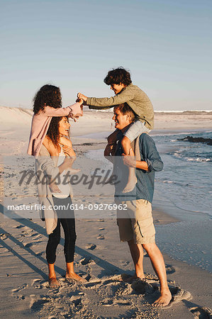 Children piggyback fighting on parents at beach