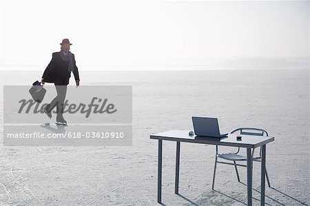 Senior Businessman Walking To Laptop On Desk On Frozen River