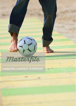 Male practicing soccer on beach
