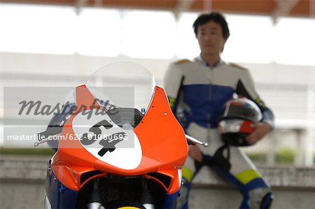 Asian racing motor biker sitting near motorcycle
